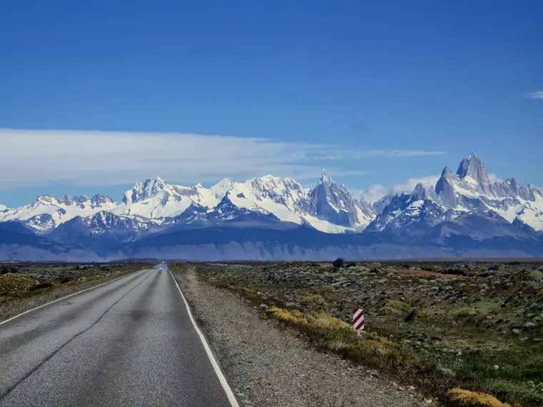 Empty road leading to snowy peaks